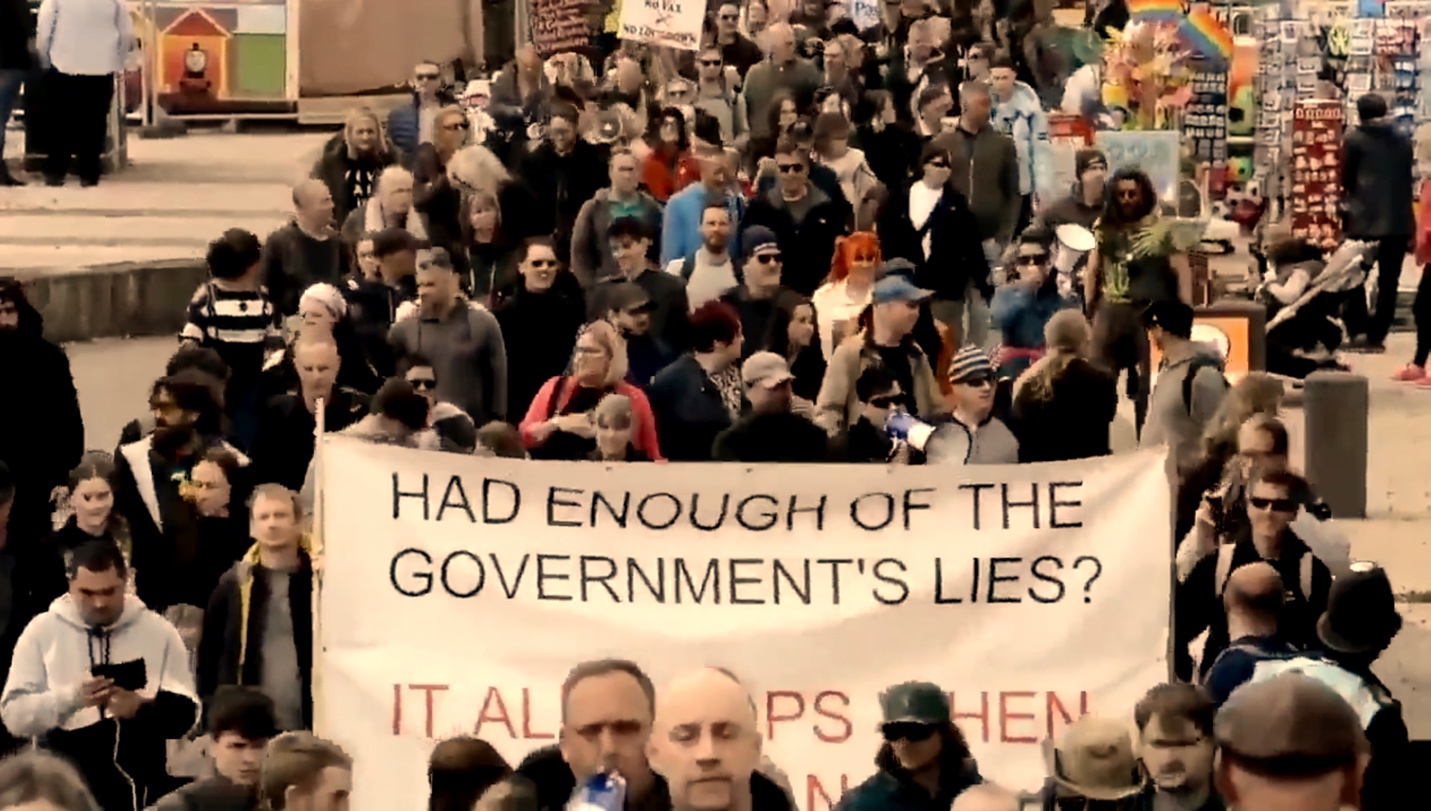 A large crowd of people holding a sign Description automatically generated with medium confidence